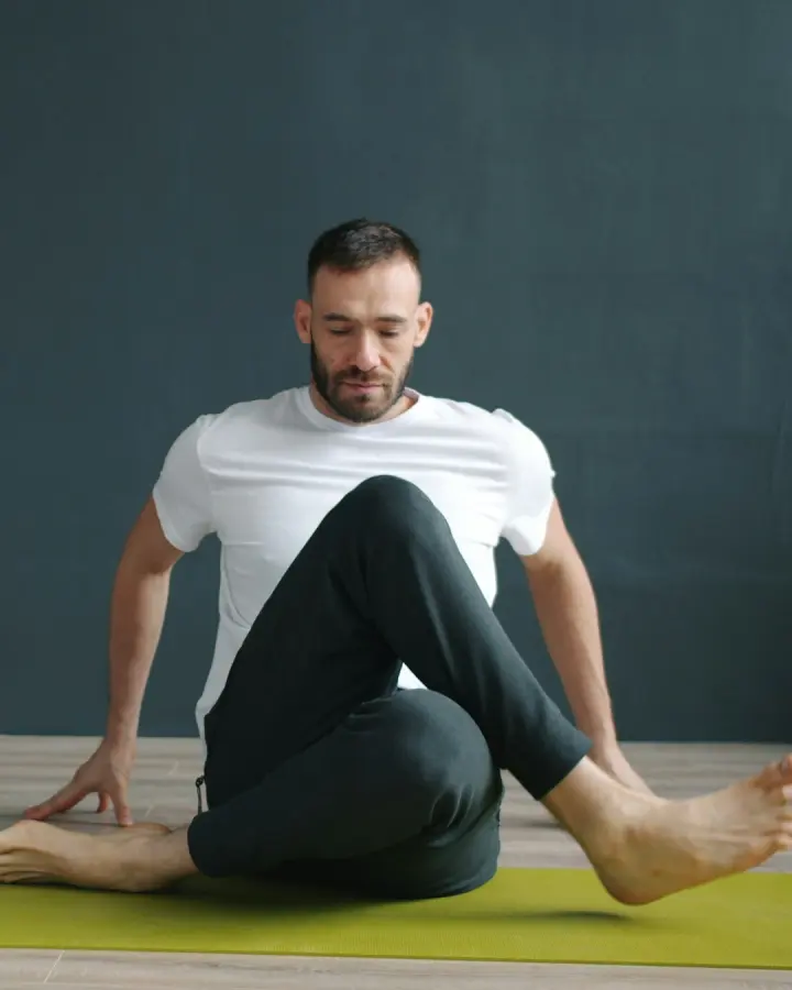 A man stretching on a yoga mat in a studio